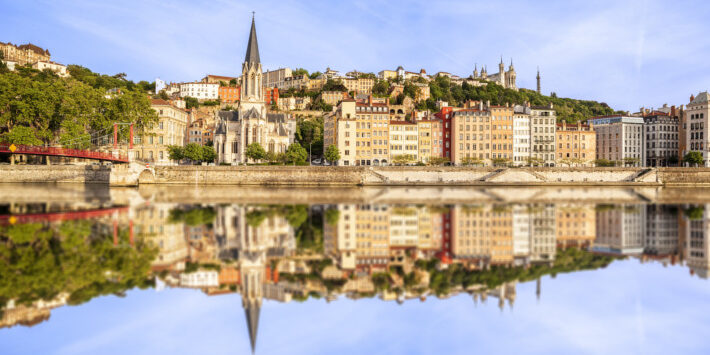 Busreisen nach Frankreich. Blick auf die Altstadt von Lyon, Frankreich, mit bunten Häusern, der Kirche Saint-Georges und Spiegelung in der Saône an einem klaren Tag.