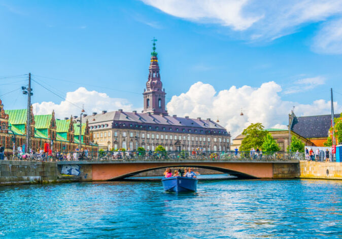 Busreisen nach Dänemark. Blick auf das Christiansborg Schloss und eine Brücke über den Kanal in Kopenhagen, Dänemark, bei sonnigem Wetter mit blauem Himmel.