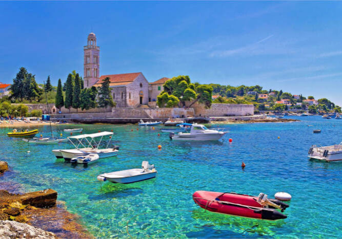 Hvar Kroatien Eine Kirche auf der Insel Hvar mit Blick auf das Meer und kleine Fischerboote.