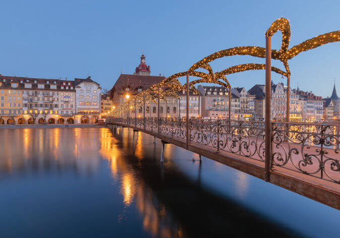 Luzern Advent Festlich geschmückte Altstadt von Luzern im Advent mit Lichterketten, Weihnachtsmarktständen und Blick auf die Kapellbrücke bei Abenddämmerung.