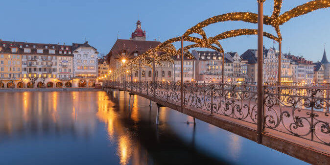 Luzern Advent Festlich geschmückte Altstadt von Luzern im Advent mit Lichterketten, Weihnachtsmarktständen und Blick auf die Kapellbrücke bei Abenddämmerung.
