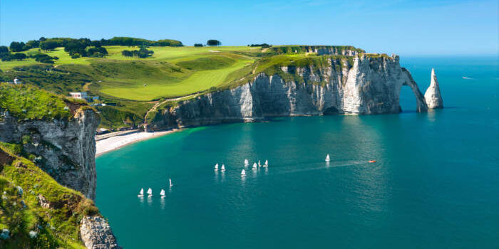 Normandie_67470107 Kreidefelsen von Étretat an der Alabasterküste in der Normandie, Frankreich, mit blauem Meer und grünen Wiesen an einem sonnigen Tag.