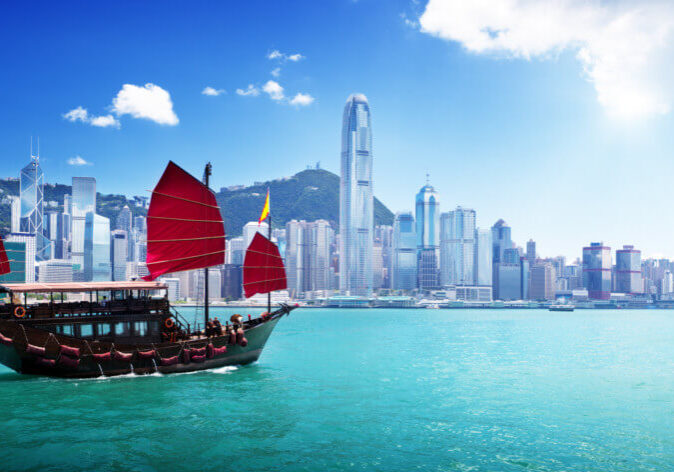 Reisen-China Reisen nach China. Dschunke mit roten Segeln in der Victoria Harbour Bucht vor der Skyline von Hongkong, China