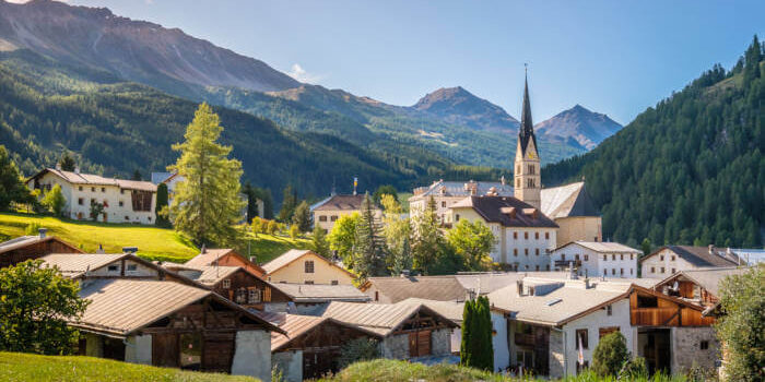 Dorf Santa Maria Val Müstair in Graubünden, Schweiz, mit Kirche, traditionellen Häusern und Bergkulisse am späten Nachmittag.