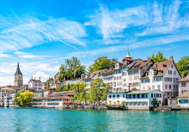 Altstadthäuser von Zürich, Schweiz, am Ufer der Limmat mit Kirchturm und blauem Himmel. Reisen in die Schweiz.