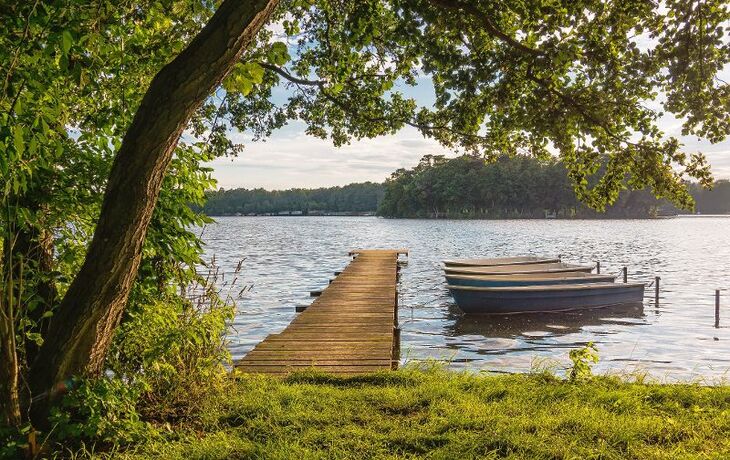 Ein Steg und Boote am See.