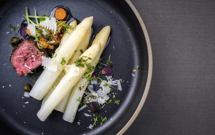 Klassischer weißer Spargel der modernen Art mit dem gegrillten gealterten geschnittenen Rinderfilet und Gemüse des Grills diente als Draufsicht auf eine minimalistic Designplatte